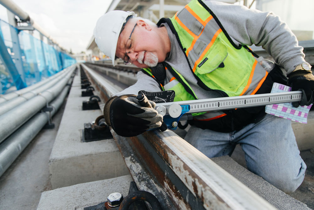 An ARM Rail Maintenance Specialist using a bar gauge to assess the rail profile